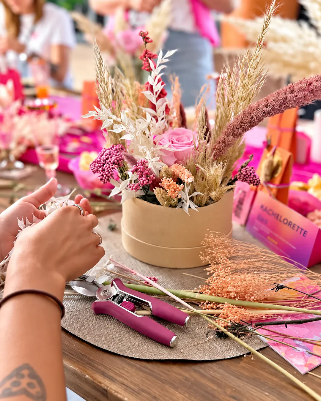 Participante composant un arrangement de fleurs séchées lors d'un atelier créatif de La Rose des Sables By Saliha